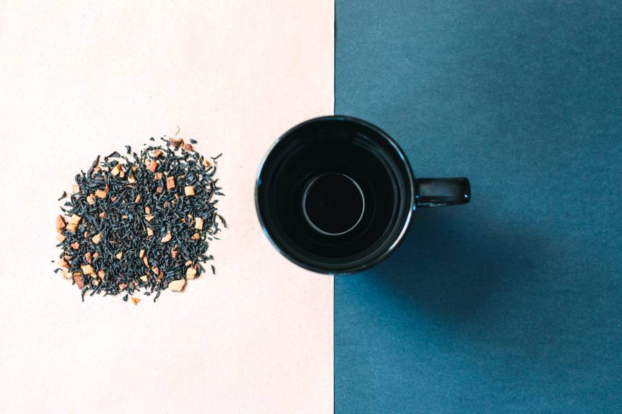 black tea leaves in a pile near an empty mug