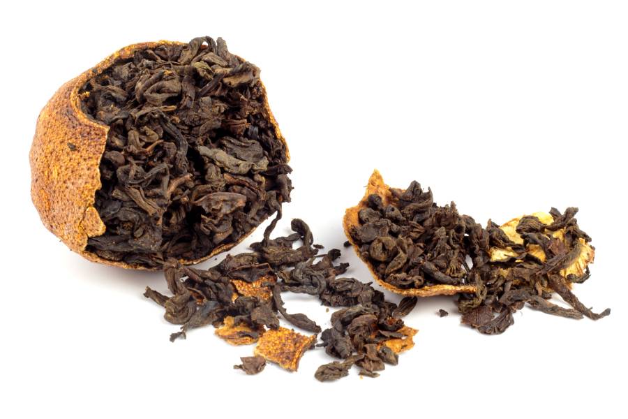 pu-erh tea leaves pouring out of a fermented orange peel